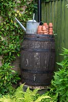 A wooden barrel water butt, fed with rainwater from a garage roof.