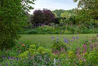 Open vistas and overflowing beds of alliums and herbaceous perennials make for a relaxed natural feel, whilst trees, box hedges and clipped balls give structure.