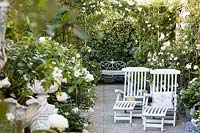 Recliners and evergreen planting in terrace garden, Milan, Italy. 