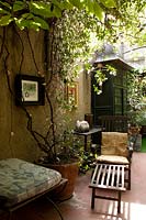 A sheltered terrace with seats and shade provided by trachelospermum jasminoides, ivy and amercian grapevine parthenocissus quinquefolia.