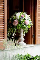 Flower arrangement in stone container on window sill with Peoni, Eryngium, Ivy, Camomile and Hydrangea