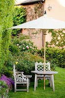 Dining area just outside the house with teak furnishings by Andrew Crace.