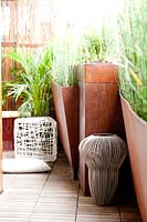 Terrace with metal containers planted with Equisetum hyemale var. robustum, artworks and furniture
