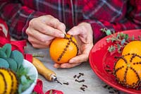 Inserting cloves into oranges