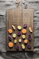 Different potato varieties displayed in wooden chopping board. 