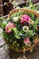 Floral arrangement in basket with roses, capsella busta pastoris, Hypericum and Eustoma. 