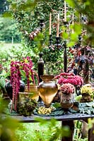 Autumn table decorated with hydrangeas, carnations, amaranth, grapes, candlesticks and metal vase