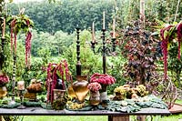 Autumn table decorated with hydrangeas, carnations, amaranth, grapes, savoy cabbage and mushrooms and candlesticks