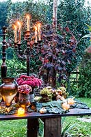 Autumn table decorated with  hydrangeas, carnations, amaranth, grapes, savoy cabbage and mushrooms and candlesticks
