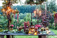 Autumn table decorated with hydrangeas, carnations, amaranth, grapes, savoy cabbage and candlesticks