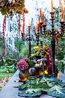 Autumn table decorated with autumn colors: hydrangeas, carnations, amaranth, pumpkins, grapes, savoy cabbage and mushrooms