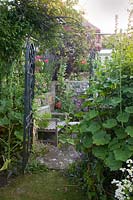 Arch gateway into a small secret walled folly with wooden seat 