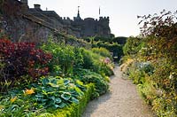 View of double border in a large country garden with long gravel pathway between borders 