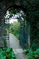 Ornate metal gate through to a separate area of the garden, arch in dividing wall