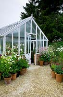 Classic greenhouse with container display at entrance on gravel