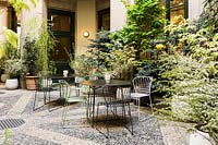 Seating areas on the cobbled patio with surrounding planting including Spiraea prunifolia plena and Tamarix gallica