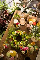 Looking down on table in a florist shop, a flower crown with candles and cut foliage and flowers