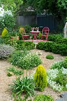 View over straw-mulched garden to red table and chairs. 