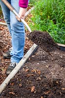 Mulching a bed in the vegetable garden with compost