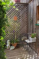 Trellis panel attached to fence and small deck, provides a corner to display a collection of ornaments and container plants 