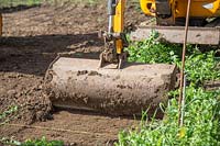 Small digger being used to scrape away top soil