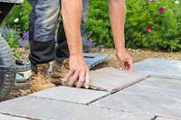 Man carefully laying a paving slab on cement
