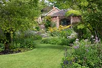 View along lawn with flower beds towards summerhouse 