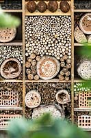 Insect house made by filling a grid of wood with sticks, logs with holes and bricks