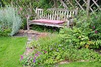 A wooden bench with flowerbeds on either side