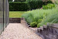 Gravel path alongside the tennis court, with steps leading up to the Loggia Garden. 