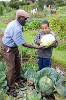 Man giving his grandson a huge Cabbage to hold