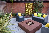 Sofa and armchairs around fire pit in small modern garden