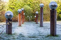 The Meadow with frosted grass and avenue of wood columns with frosted stainless steel globes. Winter