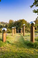 Avenue of wooden columns topped with stainless steel globes. 