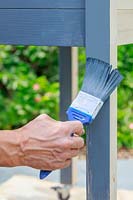 Painting a wooden raised planter with grey paint