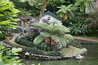 Decorative duck house near water in tropical garden 