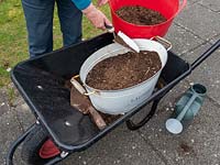 Use old containers to plant a wild flower garden.  Covering newly sewn seeds with compost 