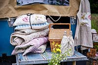 Bundle of vintage floral cushions and blankets at the back of landrover