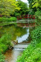 Stream flowing from lake with distant red bridge and waterfall beyond - Open Gardens Day, Nacton, Suffolk