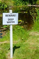 Warning sign beside deep garden pond - Open Gardens Day, Easton, Suffolk