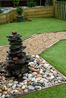 Water feature on cobbles and shingle path across artificial grass lawn - Open Gardens Day, Palgrave, Suffolk