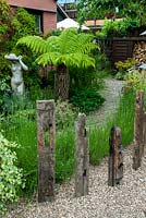 Classical statue beside Tree Fern in mixed shrub border, with Lavender and recycled wooden beams creating a feature edging to path - Open Gardens Day, Woolpit, Suffolk