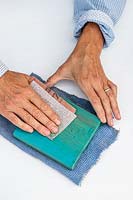 Woman using sandpaper to remove top layer of paint from the shelf and reveal the wood grain