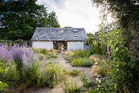 Courtyard garden with timber pergola, rill and planting including Stipa tenuissima, S. gigantea, Phlomis russeliana, Perovskia 'Blue Spire', irises and silvery stachys at Am Brook Meadow, Devon in August. 