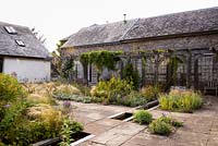 Courtyard garden with timber pergola, rill and planting including Stipa tenuissima, S. gigantea, Phlomis russeliana, Perovskia 'Blue Spire', irises,  Verbena hastata and silvery stachys at Am Brook Meadow, Devon in August. 