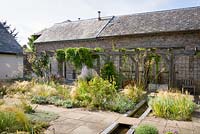 Courtyard garden with timber pergola, rill and planting including Stipa tenuissima, Perovskia 'Blue Spire', S. gigantea, Phlomis russeliana, creeping thyme and silvery stachys at Am Brook Meadow, Devon in August. 