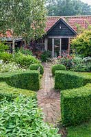 View across central circular paving area with Buxus hedging, path leading to garden studio