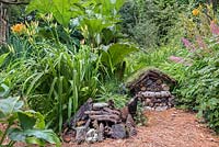 Pine needle path and insect hotel with hedgehog shelter in wildlife friendly garden 