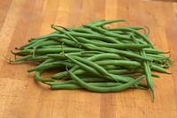 Phaseolus vulgaris 'Ferrari' - Dwarf Bean - pile of harvested beans on a chopping board