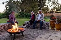 People enjoying lit firepit and having a drink